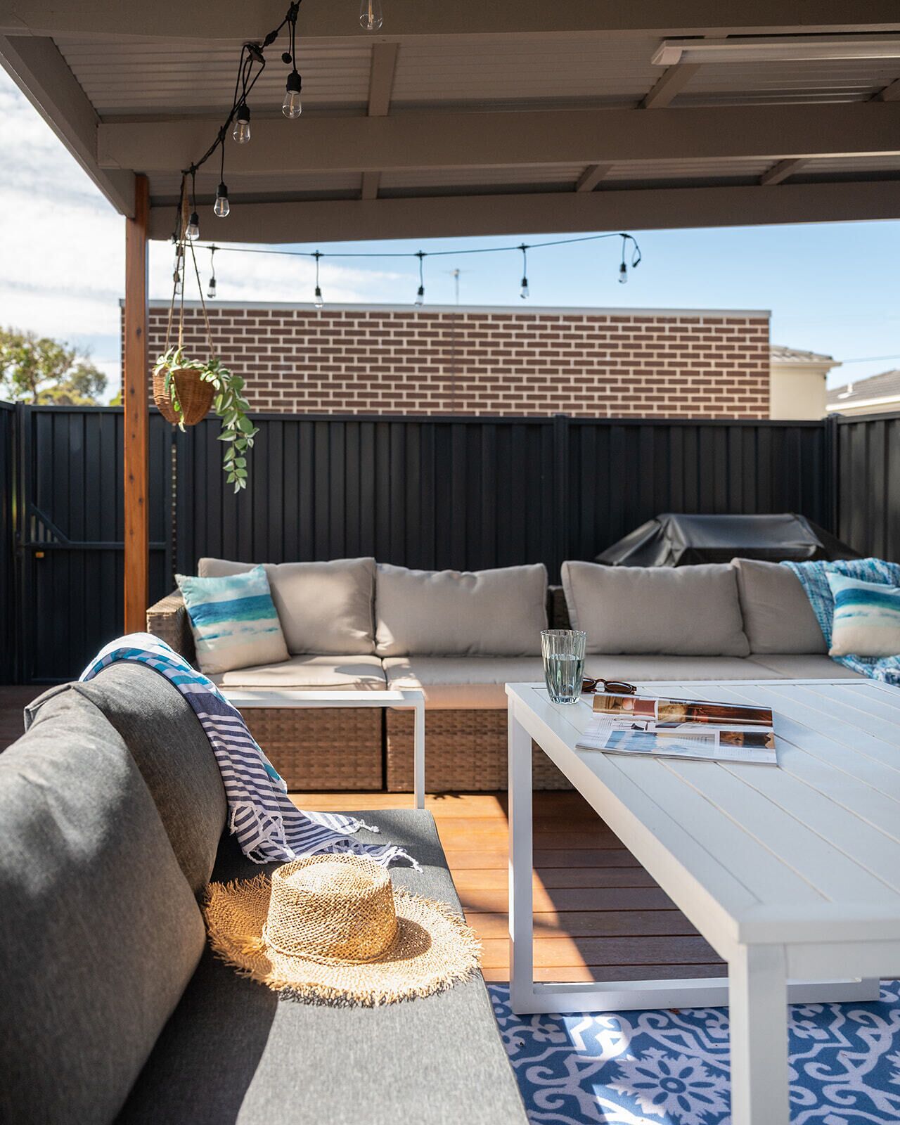 An outdoor patio with a sofa set, a white table, and string lights.