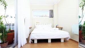 Una camera da letto con un letto, una finestra e piante in vaso.