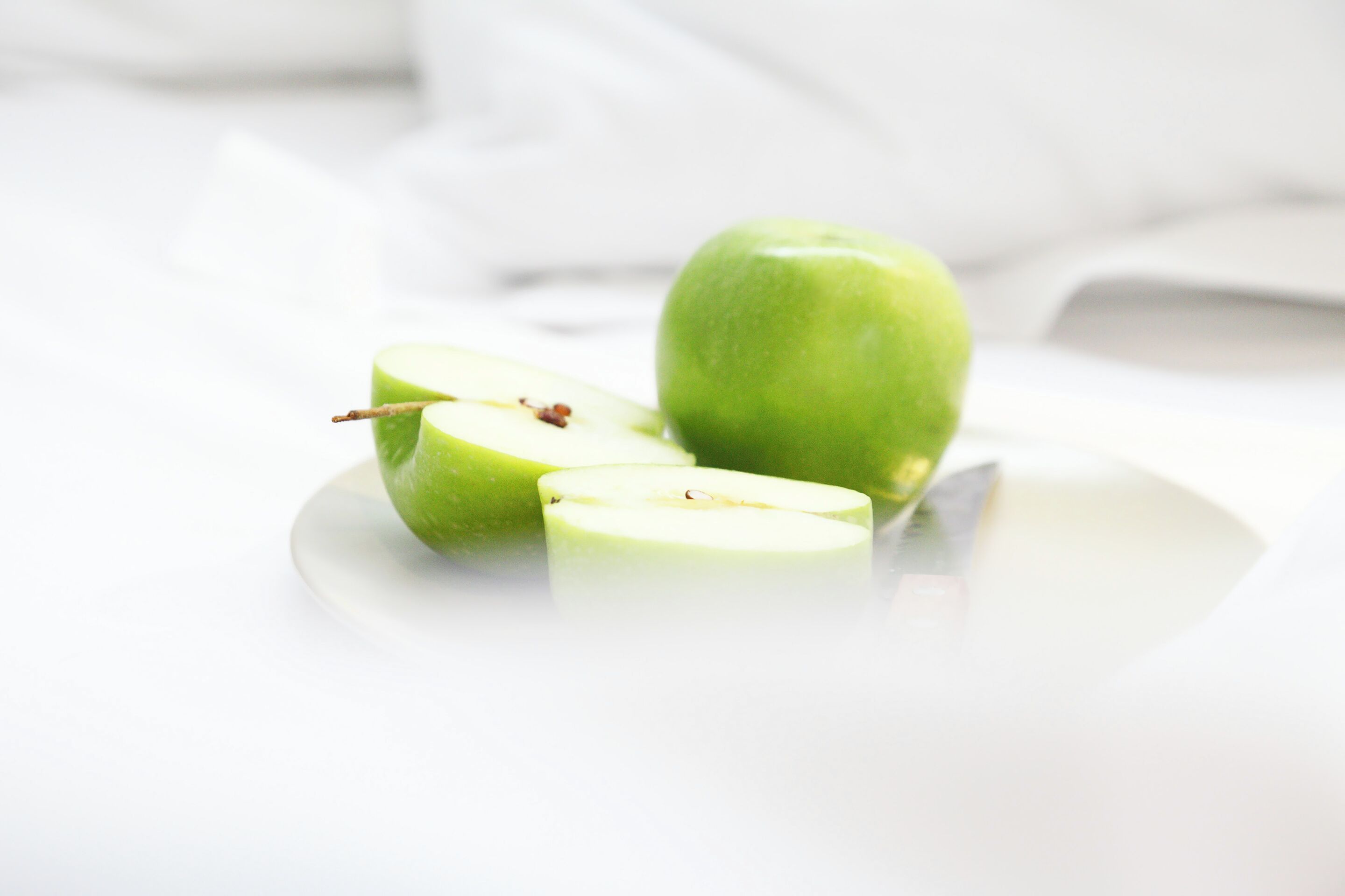A green apple on a white plate.
