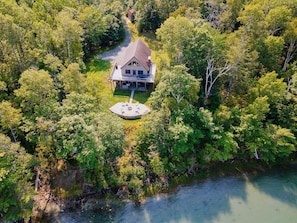 An aerial view of a house surrounded by dense trees and a body of water. - Camp Muchemore! Hot Tub, Waterfront! (Hancock)