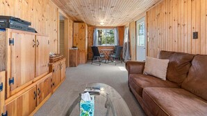 Een houten interieur met een bruine leren bank, een eettafel met stoelen en houten kasten.