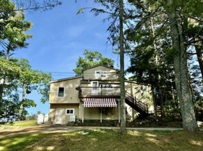 Situated among trees, this two-story building features a balcony and a staircase leading up.