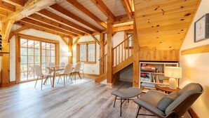 A spacious room with a wooden ceiling, a dining area with chairs, a sofa, and a staircase leading to another level. - New! Acadia Nature Escape w/Trails + Water Access (Sullivan)