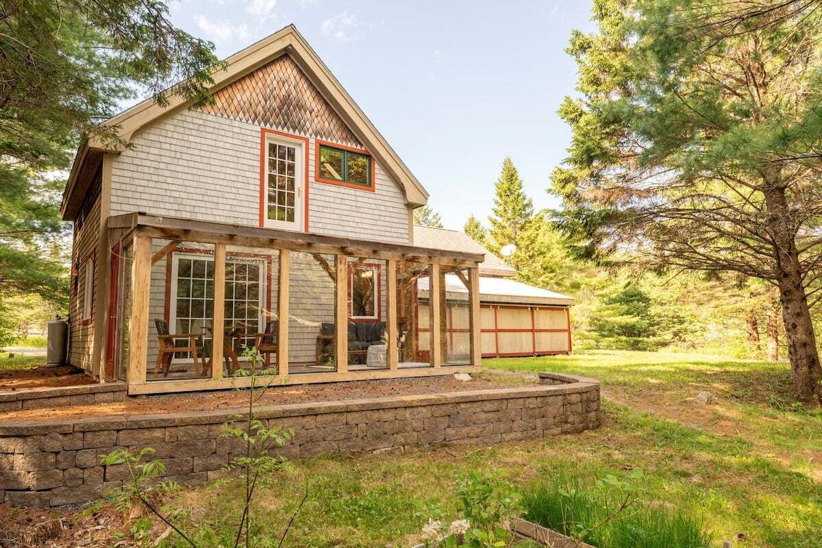 A two-story house with a covered porch, a stone foundation, and a garage.