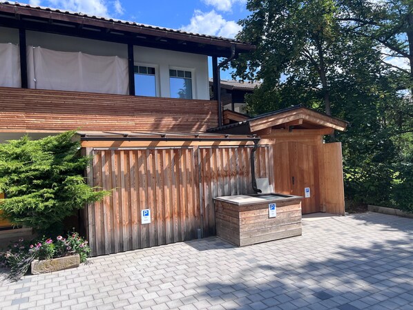 Een houten gebouw met een overdekte patio, een houten hek en een geplaveid pad.