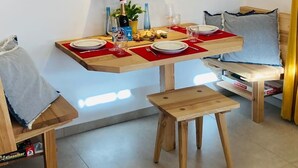 Ein gemütlicher Essbereich mit Holztisch für zwei Personen, einer Hängelampe und Wandbildern von Berglandschaften.