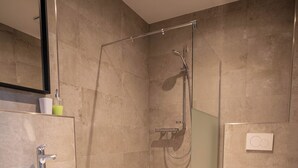 A modern bathroom with a glass-enclosed shower, a sink, and a toilet. - Apartment with shower (Garbsen)