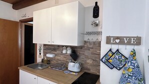 Uma cozinha compacta com armários brancos, teto de madeira, espaço para vinhos e um letreiro com a palavra 'LOVE'.