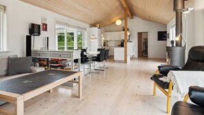 Un'ampia zona giorno con soffitto alto, camino, sala da pranzo e cucina.