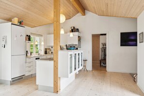 Una cocina moderna con armarios blancos, una isla central, iluminación colgante y vistas al exterior.