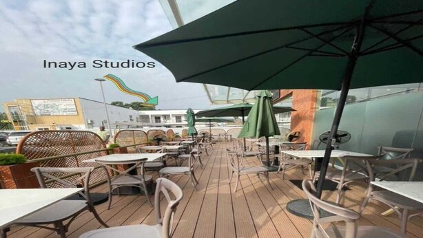 Ein Außenbereich mit Tischen, Stühlen und Sonnenschirmen, mit einem Holzdeck.