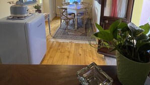 A compact kitchen with a dining area, a vintage radio, and a clock on the wall. - Vacation home (Monforte d'Alba)