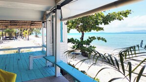 A beachside view from a covered porch with a wooden deck, a bench, and a view of the ocean. - Sand Terrace Beach Bungalows (Ko Pha-ngan)
