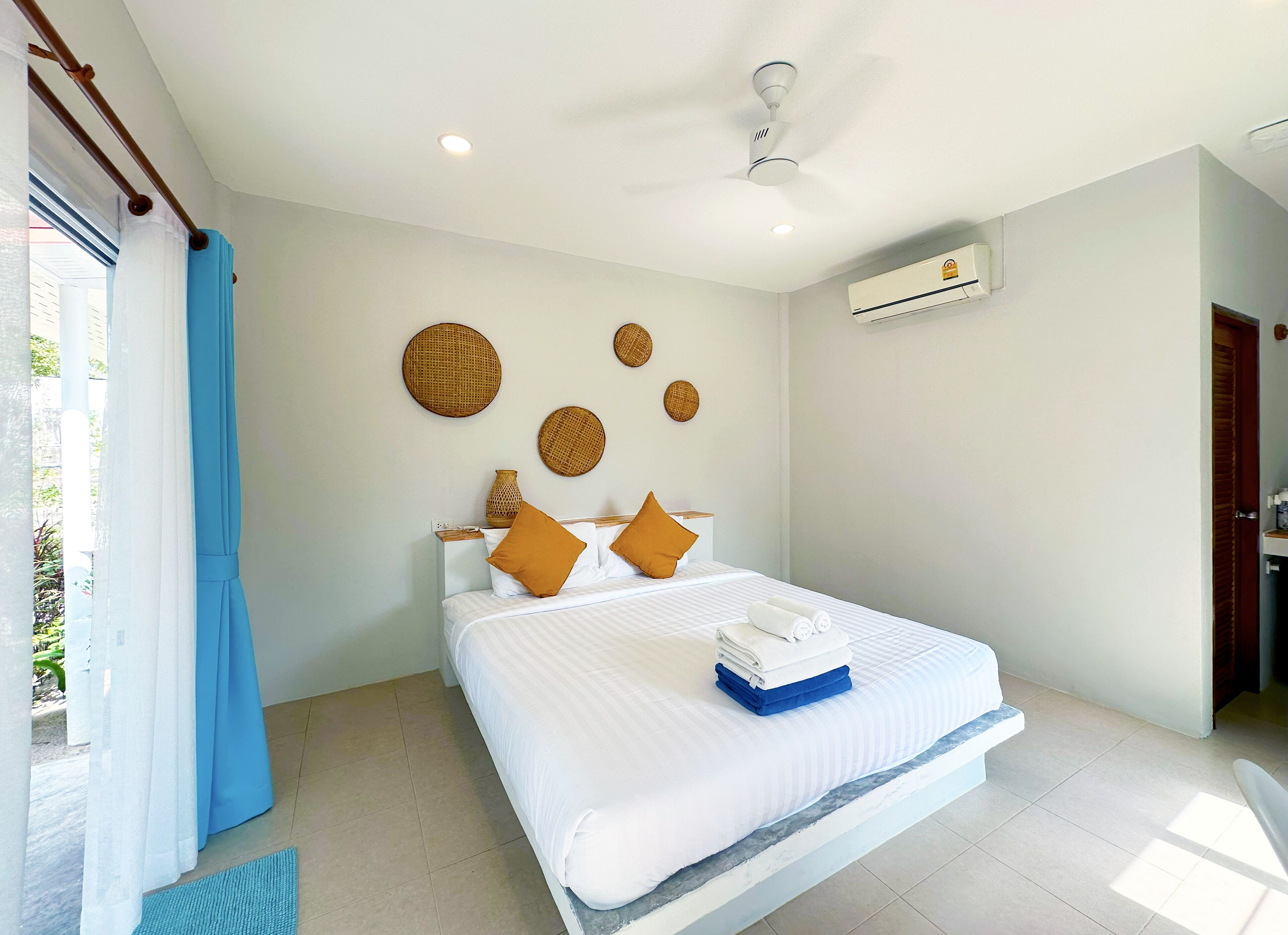 A modern hotel room with a large bed, a ceiling fan, and a view of the outdoors.
