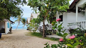 A beachside property with a sandy path leading to a white building with a balcony. - Sand Terrace Beach Bungalows (Ko Pha-ngan)