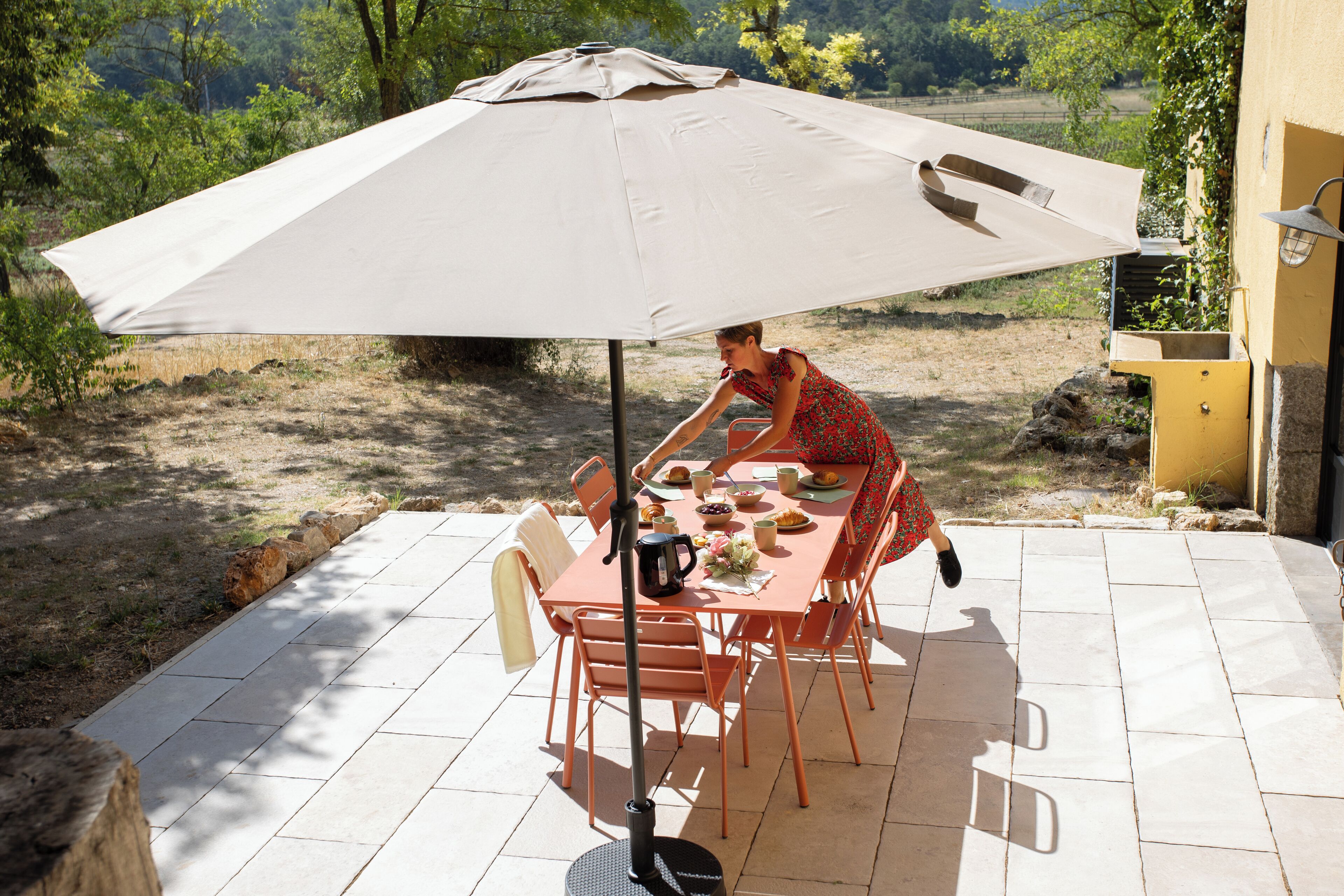 A patio with a table and chairs, an umbrella, and a person seated.