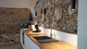 Eine moderne Küche mit Steinwand, Holzarbeitsplatte und integriertem Spülbecken.