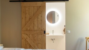 Ein Schlafzimmer mit einer Holztür, die sich gleitend in ein Badezimmer öffnet.
