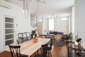 Un espai modern d'estar amb taula de dinar de fusta, cadires negres, un sofà i una taula de centre de vidre.