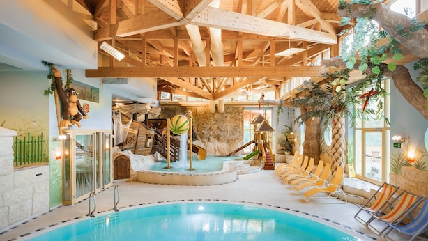 An indoor swimming pool with wooden beams, slides, and lounge chairs. - miaflor Familien- & Aktivresort (Ried im Oberinntal)