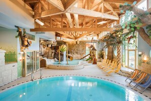 An indoor swimming pool with wooden beams, slides, and lounge chairs. - miaflor Familien- & Aktivresort (Ried im Oberinntal)