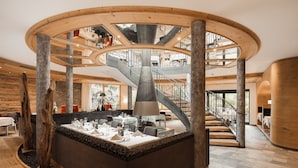 A modern interior with a central island, wooden beams, and a spiral staircase. - miaflor Familien- & Aktivresort (Ried im Oberinntal)