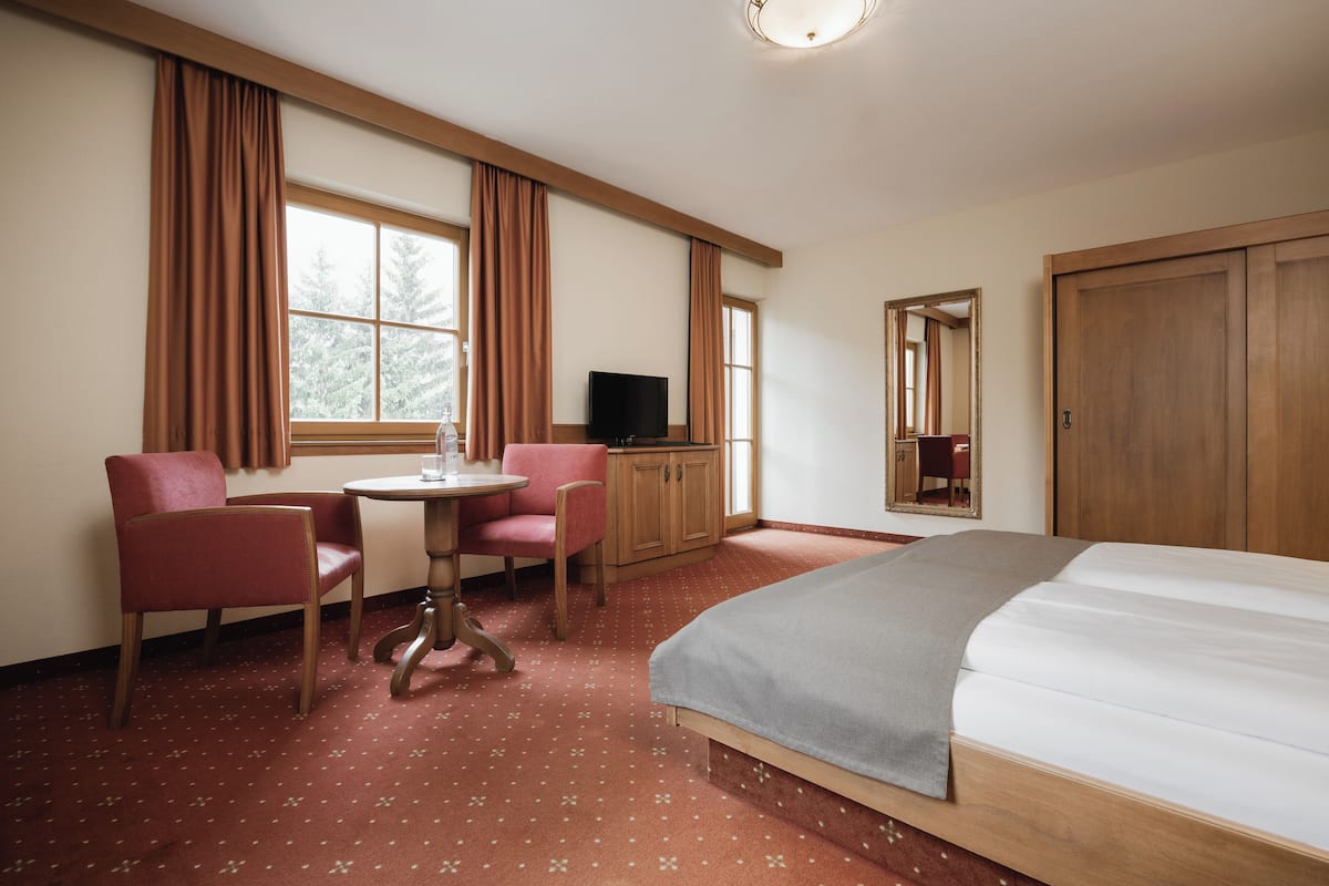Ein Hotelzimmer mit Bett, Schreibtisch mit Stuhl, Fernseher und Kleiderschrank.