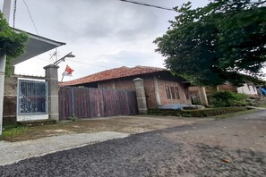 Un edificio residencial con entrada protegida por un portón, techo de tejas e izado de bandera.