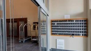Un hall d’hôtel avec un comptoir d’accueil, un téléphone fixé au mur et une collection de valises noires exposées.