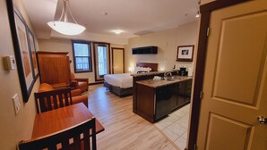 Une chambre d’hôtel compacte comprenant un coin cuisine, un espace repas, un lit et une salle de bain.