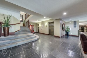 A spacious lobby with a curved staircase, a reception desk, and a large potted plant. - Mtn Views + Bunk Room / Pool, Hot Tub, Sleeps 6 (Fernie)