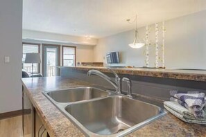 A kitchen with two stainless steel sinks, a countertop, and a hanging light fixture.
