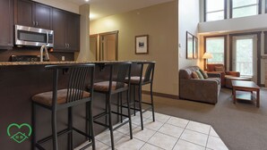 Una cocina moderna con microondas, taburetes de bar y una zona de comedor con sofá y mesa.