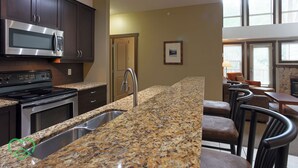 Una cocina moderna con encimeras de granito, electrodomésticos de acero inoxidable y un comedor con sillas de cuero.