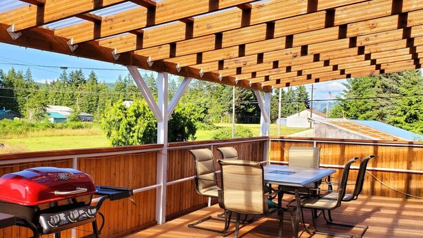 An outdoor patio with a wooden deck, a barbecue grill, and a table with chairs. - Soaring Heights Loft, Home Away From Home (Forks)