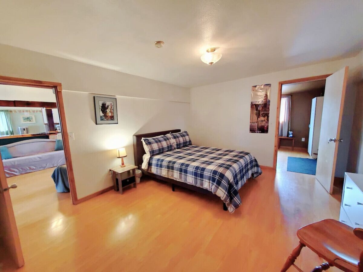 A bedroom with a bed, bedside table, and a door leading to another room.