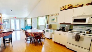 A kitchen with wooden flooring, a round dining table with chairs, white cabinets, a stove, and a microwave. - Soaring Heights Loft, Home Away From Home (Forks)
