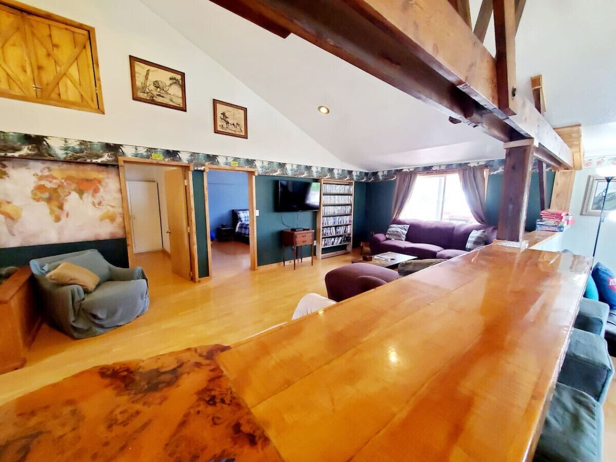 A spacious living area with a wooden bar, a sofa, a bookshelf, and a television.