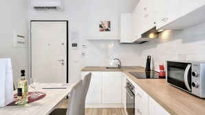 A modern kitchen with white cabinets, a microwave, and a sink. - Wine Apartments Florence Bardolino (Firenze)
