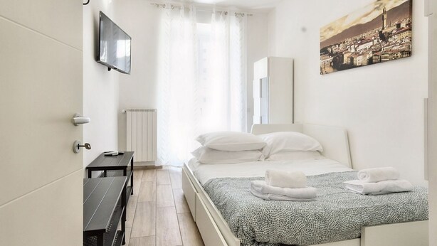 A modern bedroom with a bed, a desk, and a TV. - Wine Apartments Florence Bardolino (Firenze)