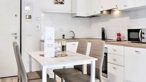 A compact kitchen with white cabinets, a microwave, a coffee maker, and a wine bottle on the counter. - Wine Apartments Florence Bardolino (Firenze)