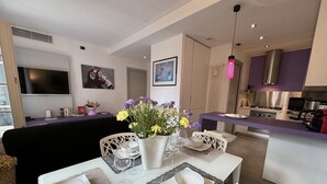 Uma sala de estar moderna com área de refeições, cozinha e televisão na parede.