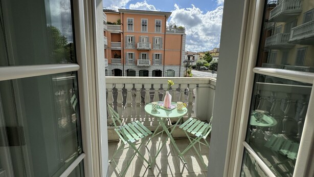 Uma varanda com mesa e cadeiras, vista para edifícios altos e céu limpo.