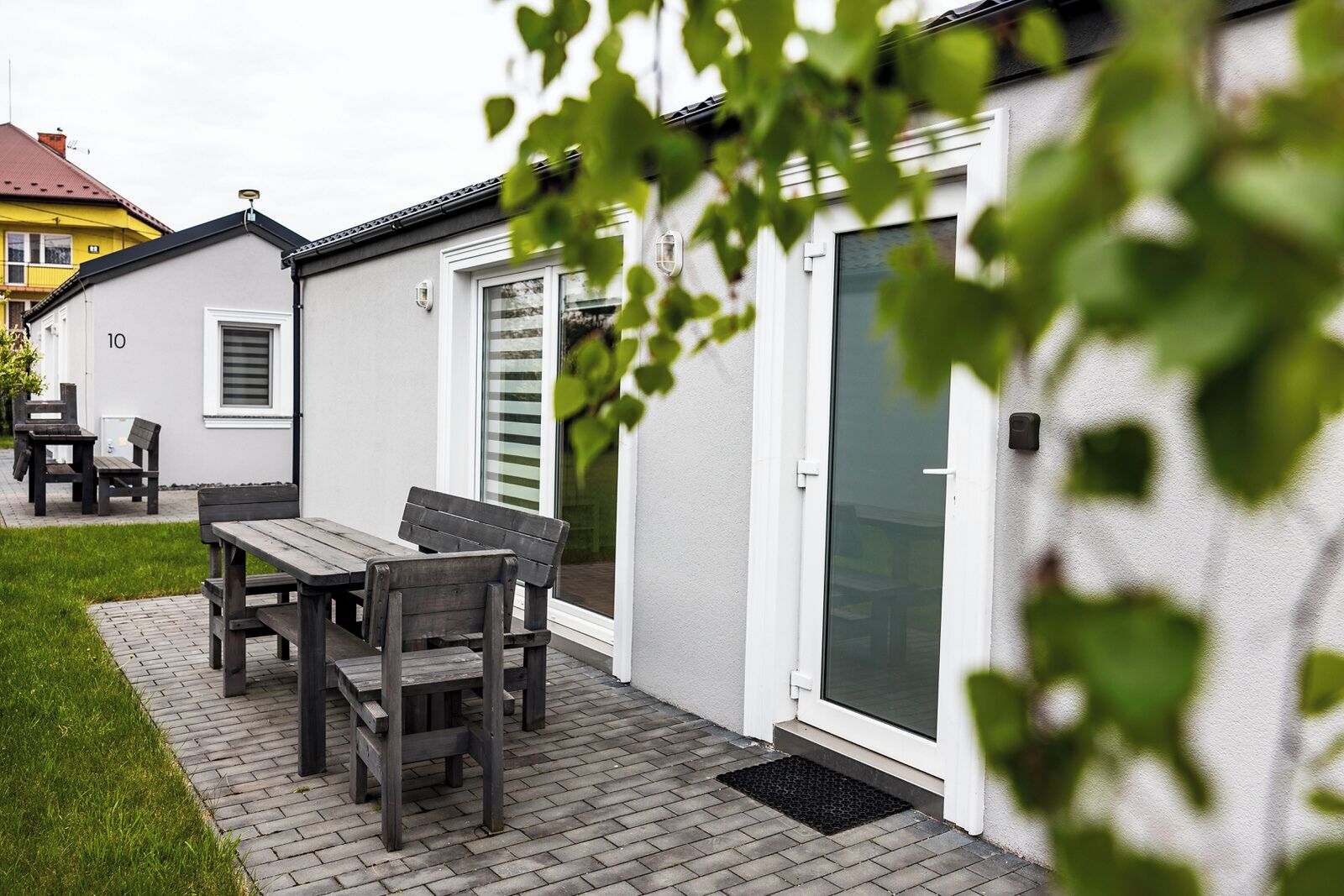 A patio with a wooden table and benches, a door, and a window.