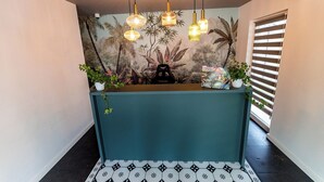Un comptoir d’accueil orné d’une fresque aux motifs tropicaux, une machine à café noire et une boîte de barres énergétiques Energy Landia.