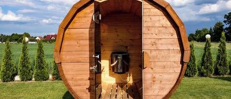 Une structure en bois en forme de tonneau, dotée d’une porte, d’un banc à l’intérieur et d’un petit chauffage.