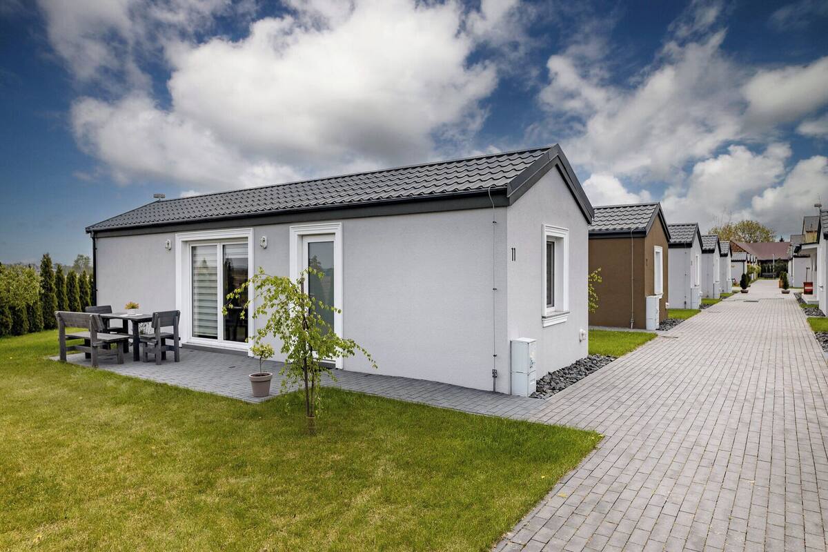 A row of modern, single-story mobile homes with a paved walkway between them.