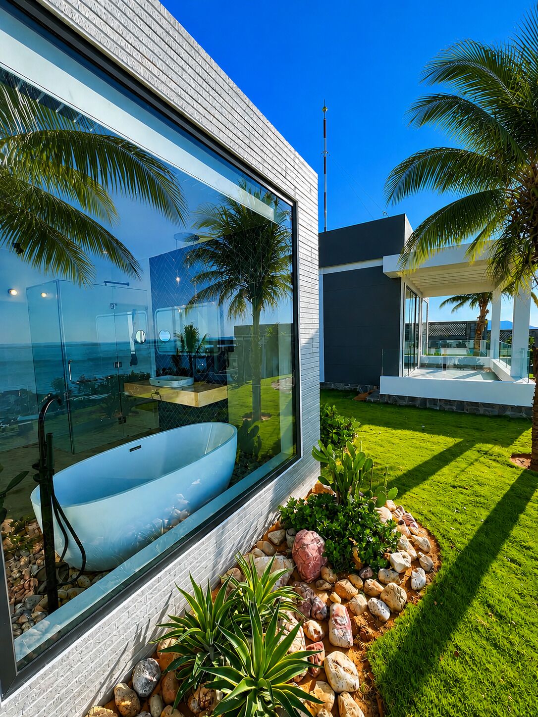 Una casa moderna con un amplio ventanal, una bañera y un jardín bien cuidado.