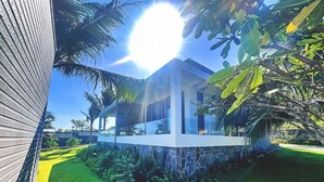 A modern house with a glass facade, surrounded by lush greenery and a well-maintained lawn. - Du Parc Resort Mũi Né (Mui Ne)