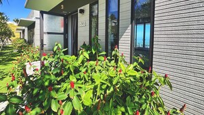 A modern building with a number '508' on the wall, large windows, and a well-maintained garden with green foliage and red flowers. - Du Parc Resort Mũi Né (Mui Ne)